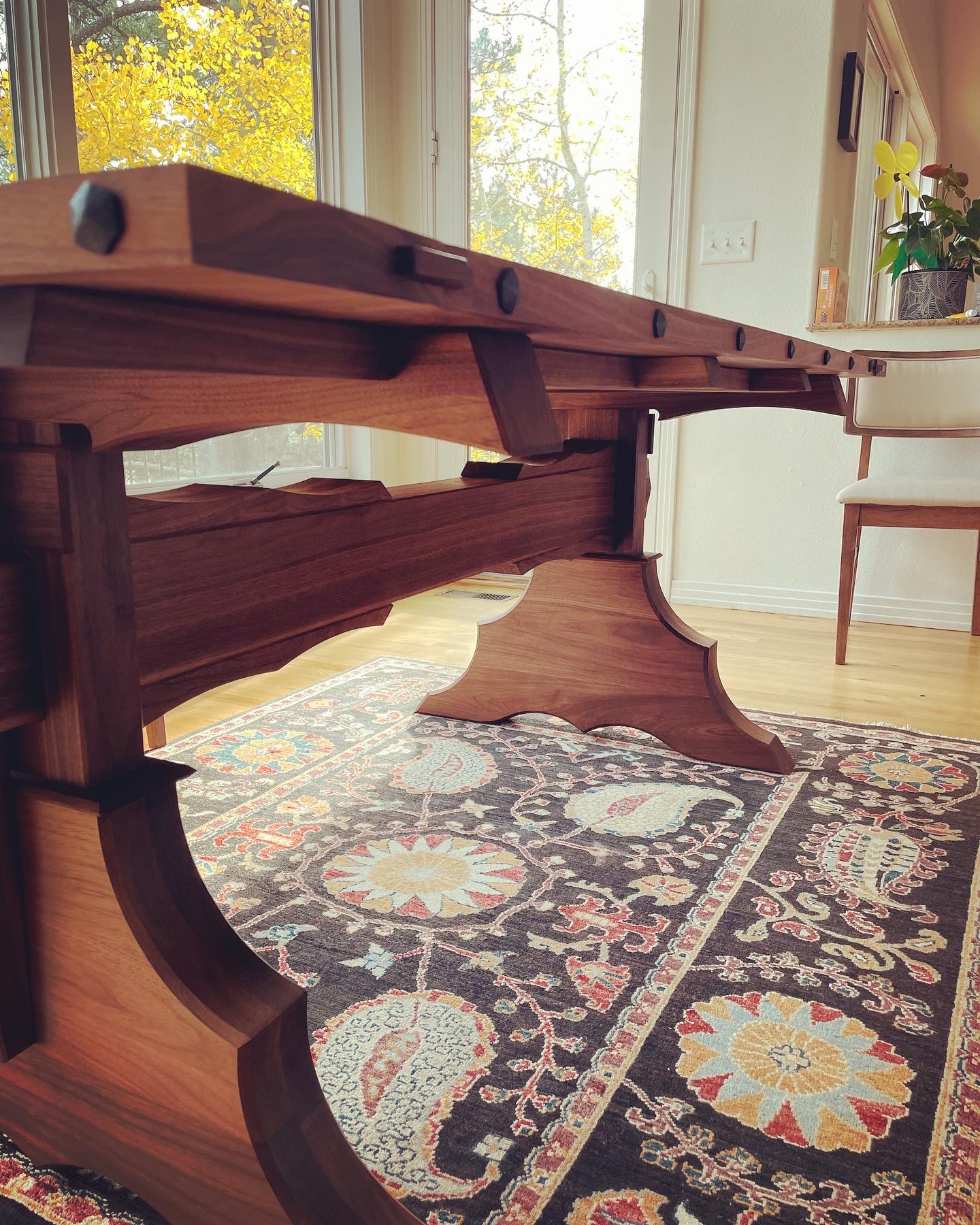 Side view of Gothic Spanish revival dining table showcasing ornate walnut trestle with clavos accents by Grillo & Co